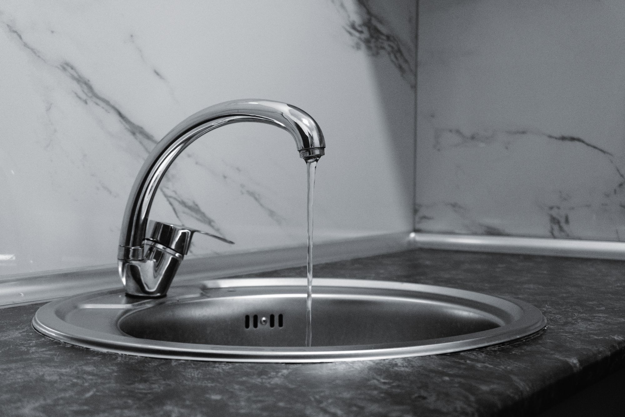 Professional plumber repairing copper pipes under a kitchen sink in Overland Park, Kansas